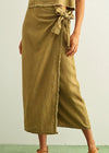 Person wearing a green wrap skirt with a plain background