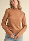Woman wearing a brown sweater against a beige background