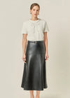 Woman wearing a white blouse with a bow and a black leather skirt on a beige background