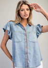 Woman wearing a denim shirt with ruffled sleeves against a plain background