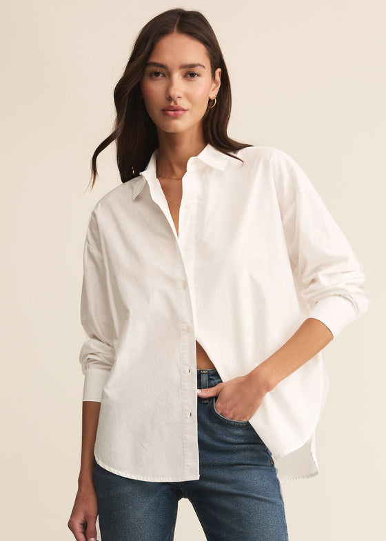Woman wearing a white shirt and blue jeans on a beige background