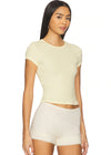 Woman wearing a light yellow top and white shorts on a white background