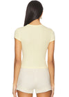 Woman wearing a light yellow ribbed top and shorts set on a white background
