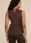 A woman shown from the back wearing a sleeveless peplum top and matching pants with a black and pink polka dot pattern, set against a plain beige studio background.