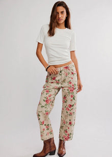  Woman wearing a white t-shirt and floral pants on a plain background