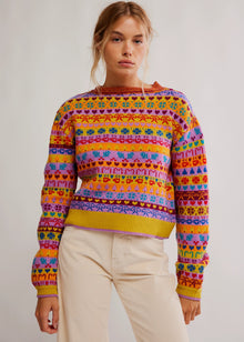  Person wearing a colorful patterned sweater against a plain background