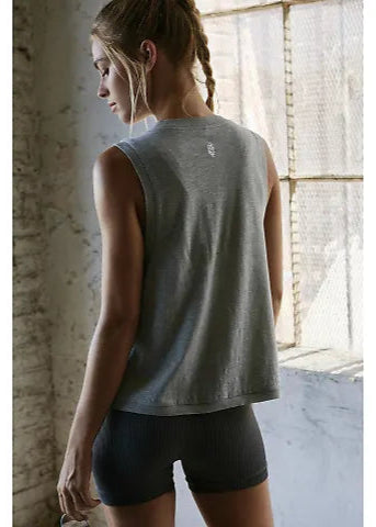 Woman wearing a gray sleeveless top and black shorts in a room with a window.