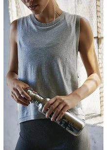  Person holding a water bottle indoors with a neutral background