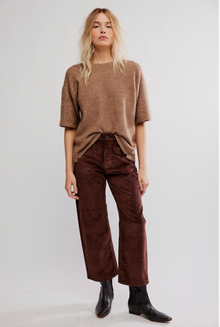  Woman wearing a brown sweater and corduroy pants on a white background