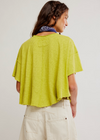 Person wearing a green top and beige pants against a plain background