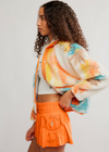 Woman wearing a colorful jacket and orange shorts against a white background