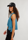 Woman wearing a black cap and blue sleeveless top against a white background