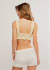 Woman wearing a beige lace top and shorts on a plain background