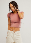 Woman wearing a pink crop top and beige pants on a plain background
