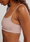Person wearing a light pink sports bra on a plain background