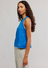 Woman wearing a blue sleeveless top with a logo on a plain background