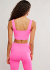 Person wearing a pink sports bra and leggings set on a light gray background