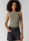Woman wearing a green tank top and black shorts against a plain background