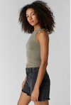 Woman wearing a green tank top and black shorts against a plain background