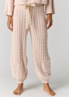 A person wearing light blush pink cable-knit harem-style lounge pants with a cream drawstring, shown from the waist down against a plain light gray studio background.