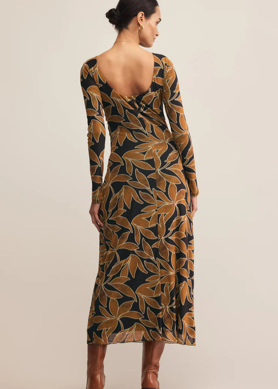 Woman wearing a long-sleeve dress with a leaf pattern on a beige background