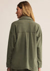 Person wearing a green jacket on a beige background