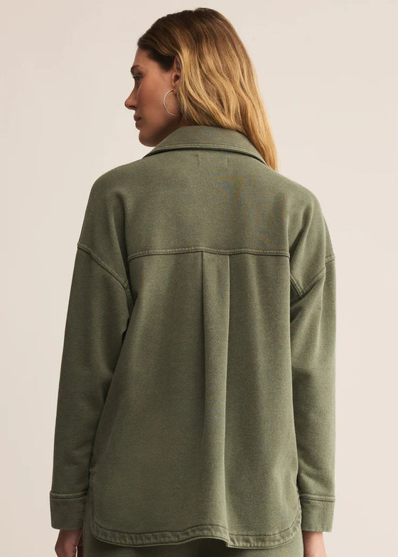 Person wearing a green jacket on a beige background
