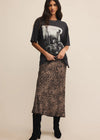 Woman wearing a graphic t-shirt and leopard print skirt on a beige background