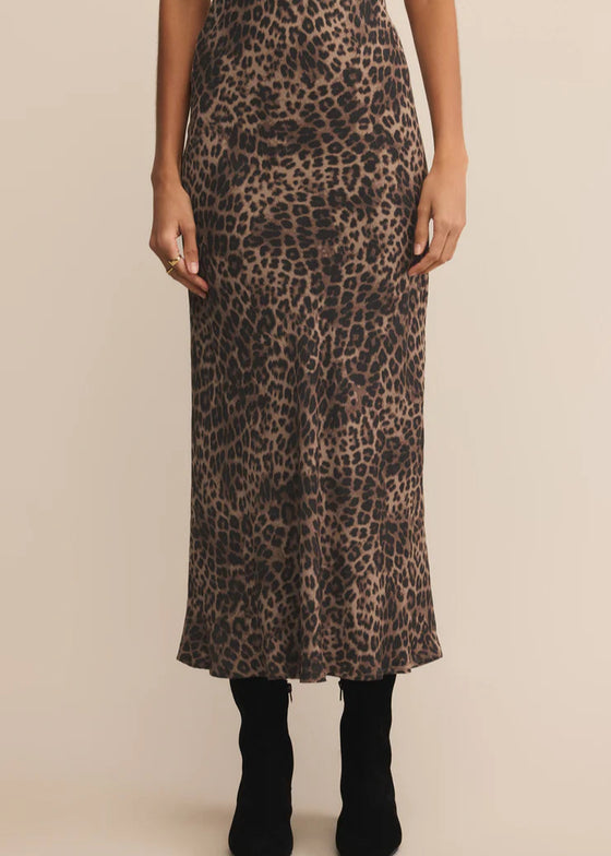 Person wearing a leopard print skirt on a beige background