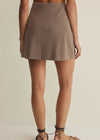 Person wearing a brown skirt on a beige background
