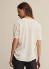 Person wearing a white t-shirt and black pants on a beige background