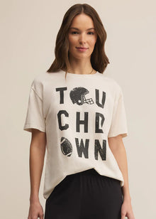  Woman wearing a beige t-shirt with 'TOUCHDOWN' print on a beige background