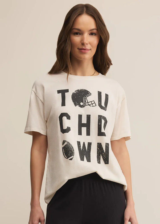 Woman wearing a beige t-shirt with 'TOUCHDOWN' print on a beige background