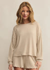 Woman wearing a beige ribbed lounge set against a plain background