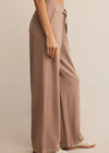 Person wearing beige wide-leg pants on a plain background