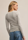 Woman wearing a striped long-sleeve top and blue jeans against a plain background
