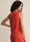 Woman wearing a red sleeveless top and pants against a beige background