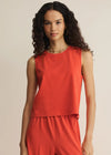 Woman wearing a red sleeveless top and pants on a beige background