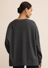 Person wearing a dark gray sweater on a beige background