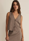 Woman wearing a brown sleeveless top and skirt set against a beige background