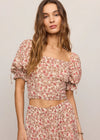 Woman wearing a floral two-piece outfit against a plain background