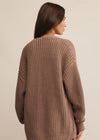 Woman wearing a brown knitted sweater against a beige background