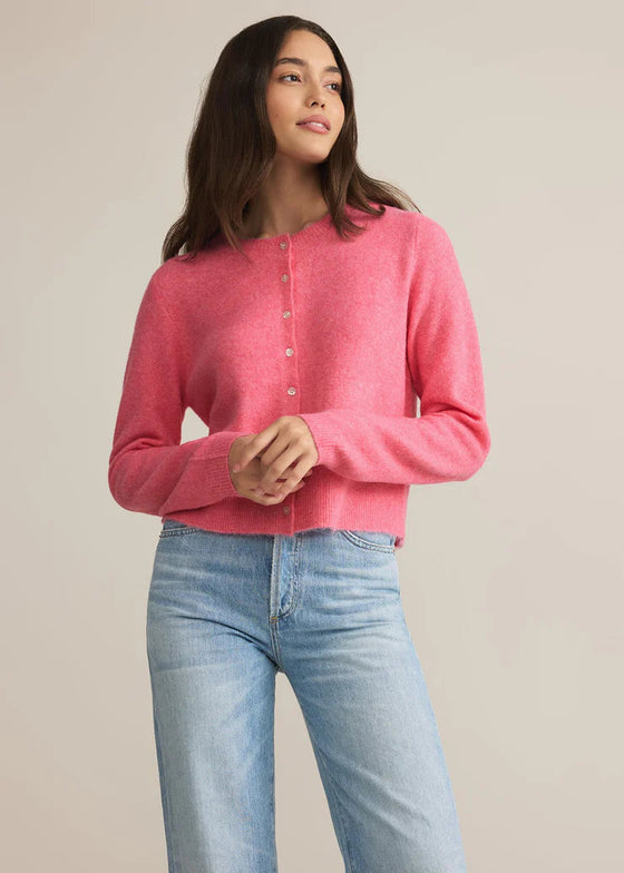 Woman wearing a pink sweater and blue jeans against a plain background