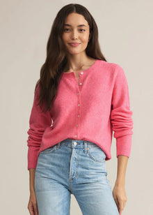  Woman wearing a pink cardigan and light blue jeans against a beige background