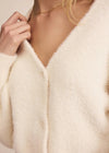 Close-up of a person wearing a cream-colored cardigan with a blurred background