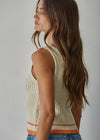 Woman wearing a beige ribbed tank top with orange trim against a plain background