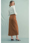 Woman wearing a white top and brown patterned skirt on a light green background