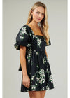 Woman wearing a black floral dress against a plain background