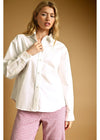 Woman wearing a white shirt and pink checkered pants against a beige background