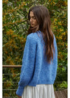 Woman wearing a blue sweater with a green foliage background